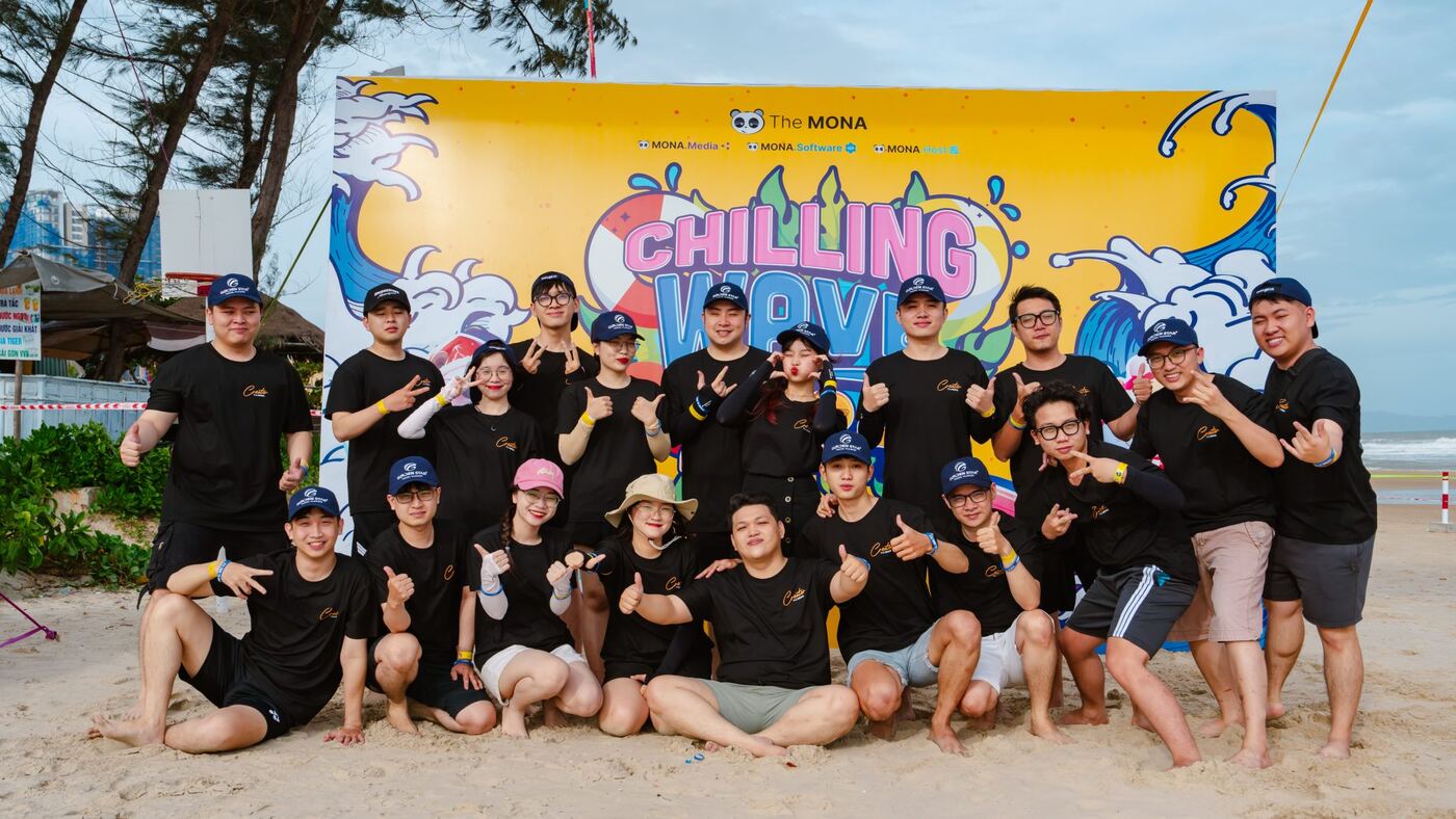 Đội ngũ MONA mặc áo đồng phục chụp ảnh team building trên bãi biển